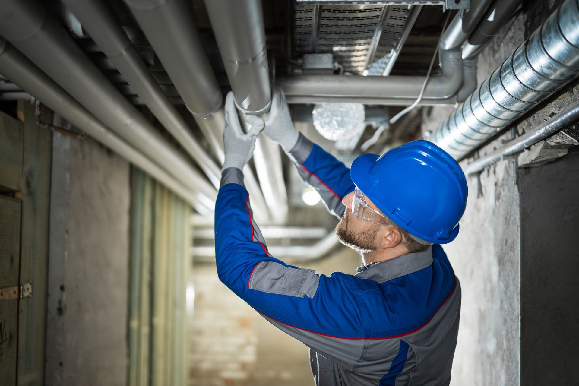 Specialists inspecting water pipes for leaks in the basement at a commercial property