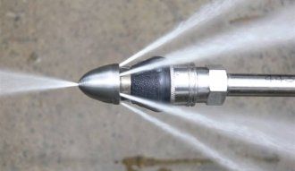 A close up of a drain cleaning nozzle spraying water.