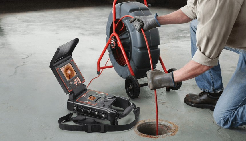 A man is using a camera to look into a hole in the floor.