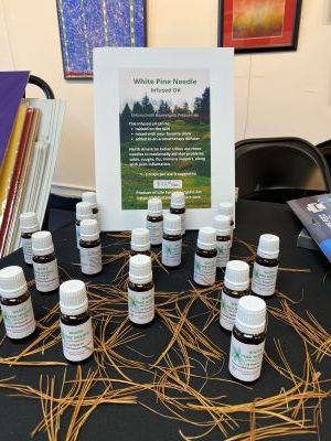 A table topped with bottles of essential white pine needle oils and pine needles.