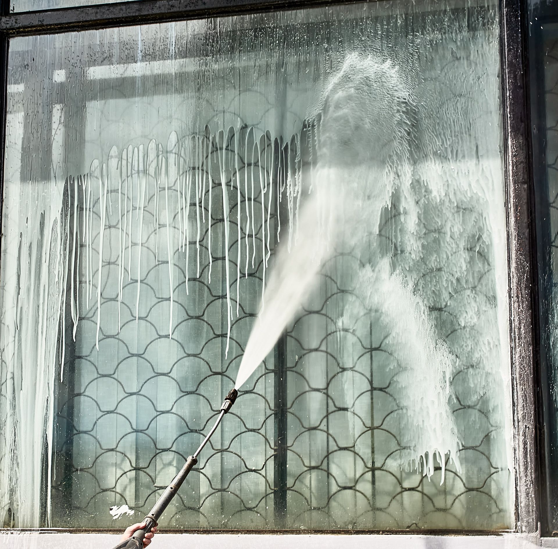 A person is cleaning a window with a high pressure washer