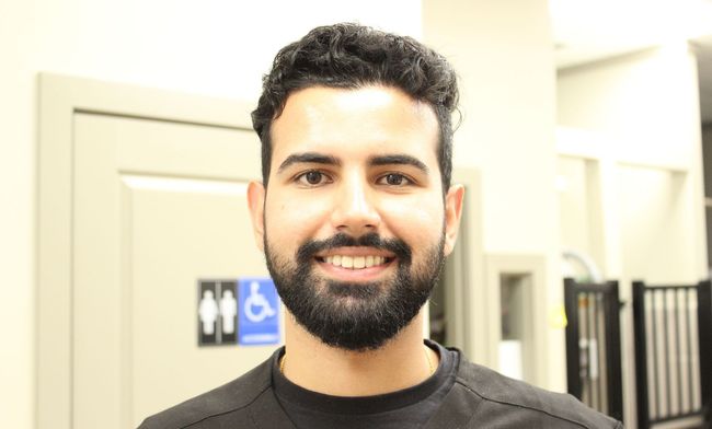 A man with a beard is smiling in front of a handicap sign.