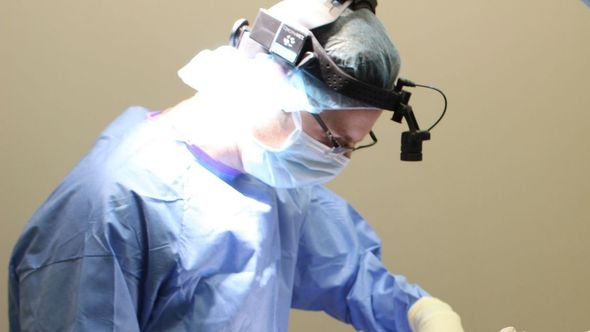 A surgeon is operating on a patient in an operating room.