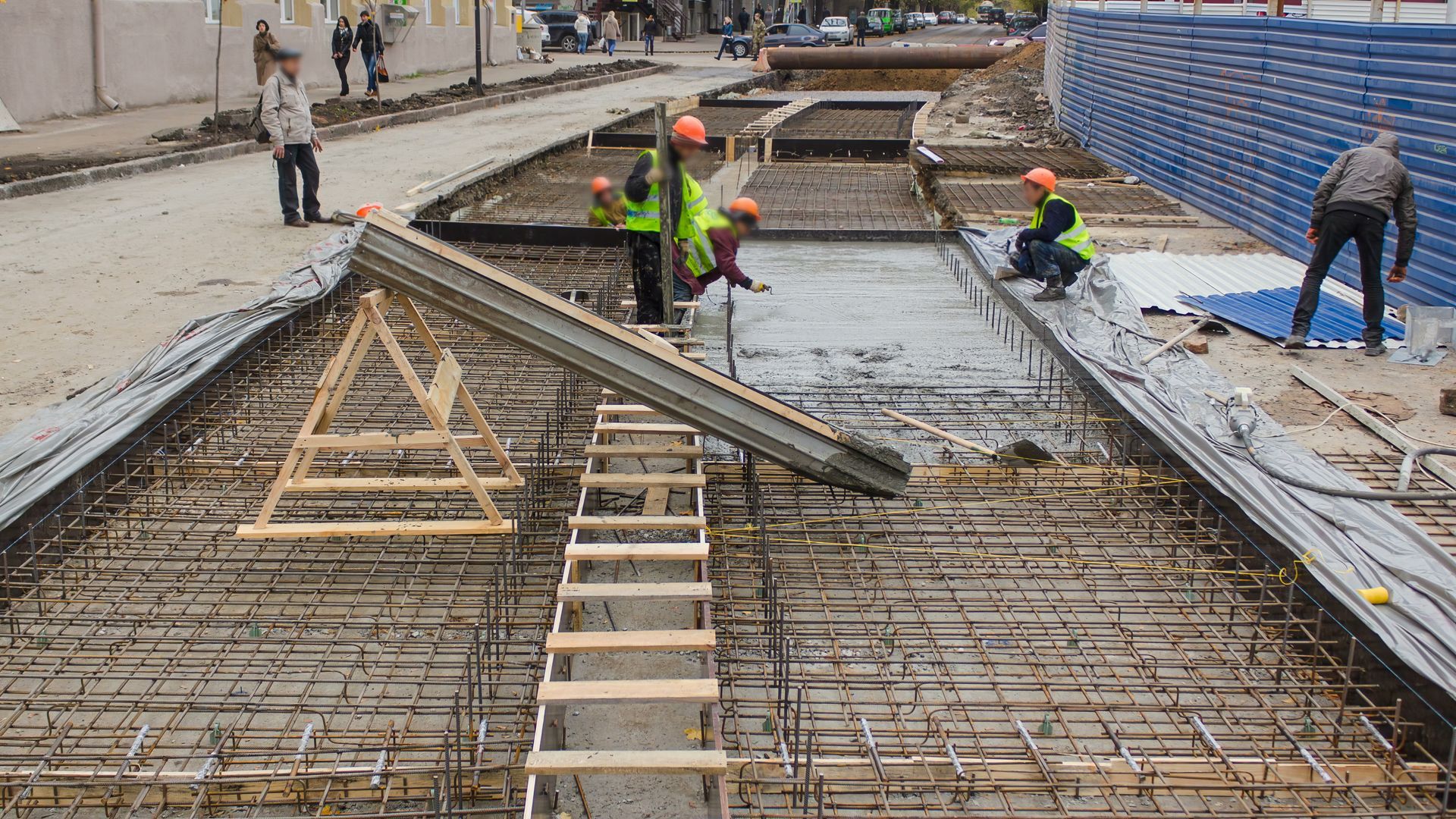 A group of construction workers are working on a concrete walkway.