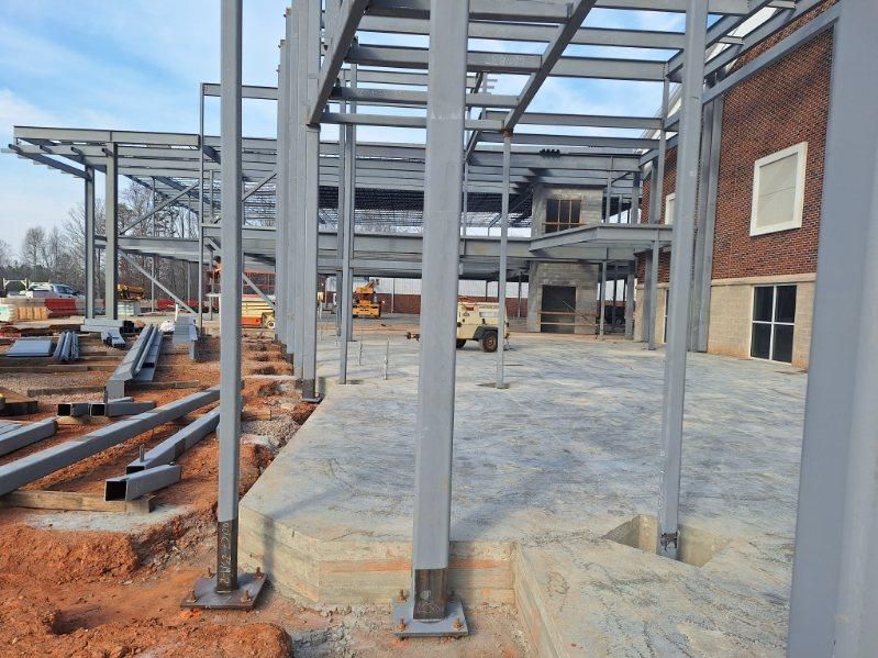 A large metal structure is being built in front of a brick building.