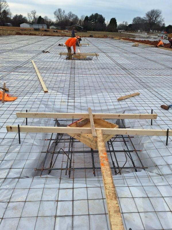 A man in an orange shirt is working on a concrete floor