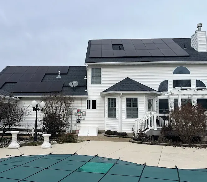 A white house with black solar panels on the roof