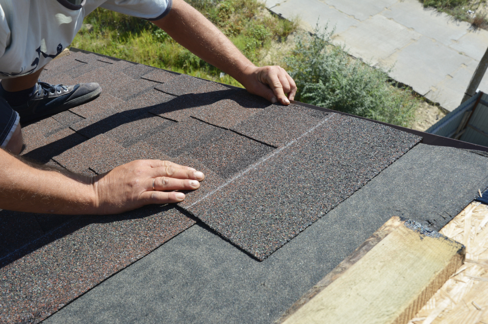 A man is laying shingles on a roof.