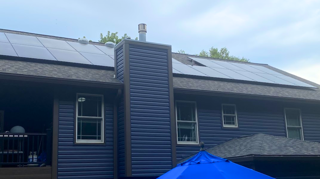 A blue house with a blue umbrella and black solar panels.