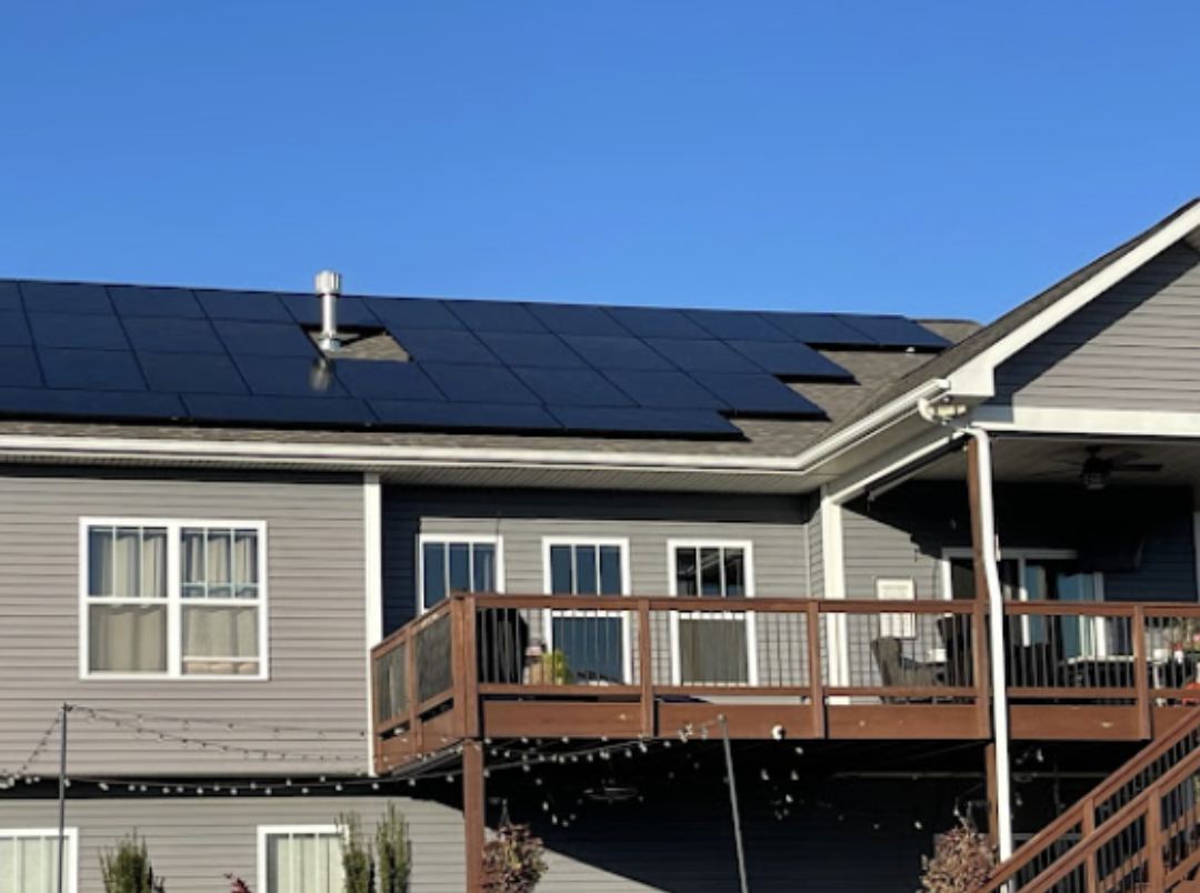 A large house with a deck and solar panels on the roof.