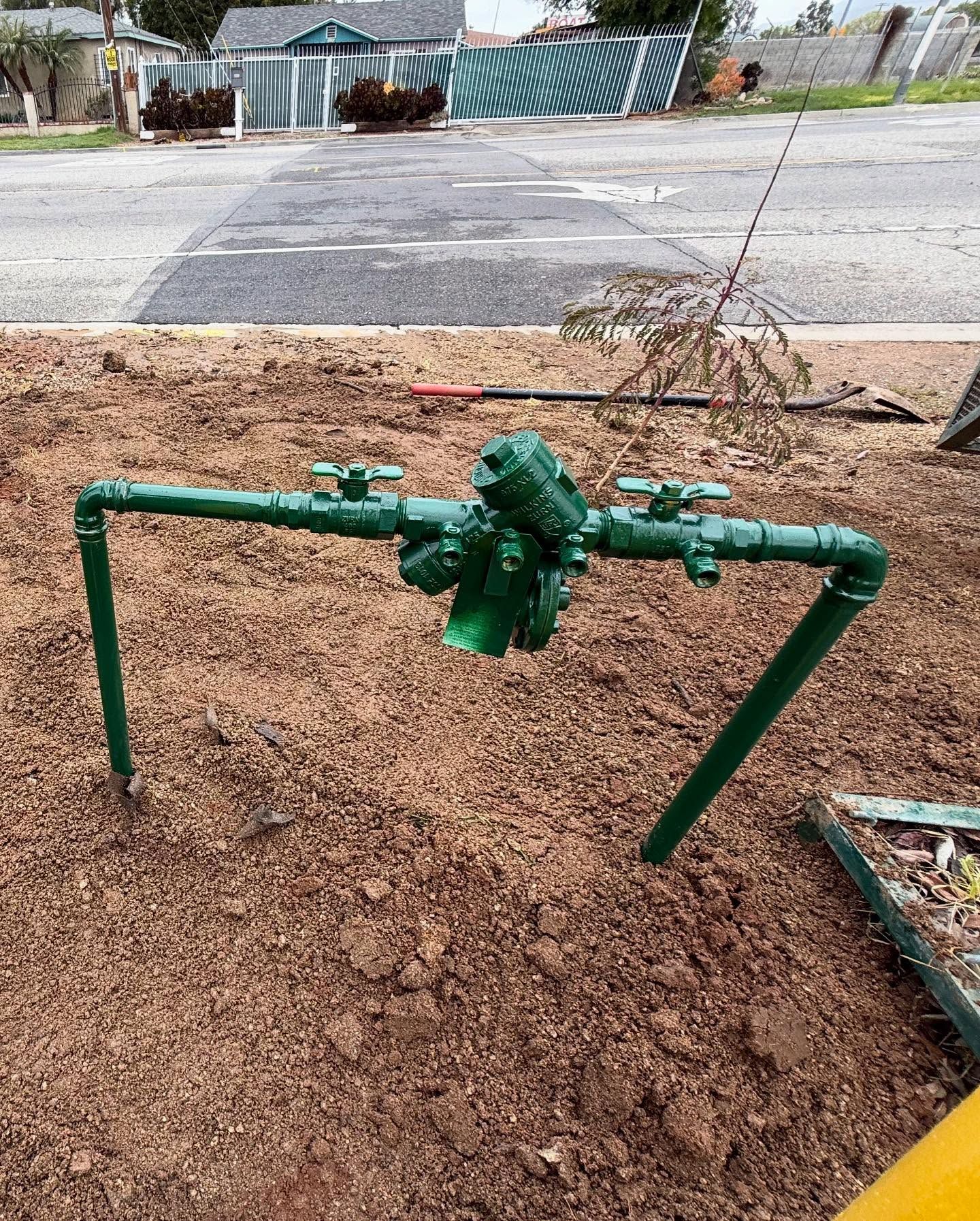 Green water valve system on dirt.