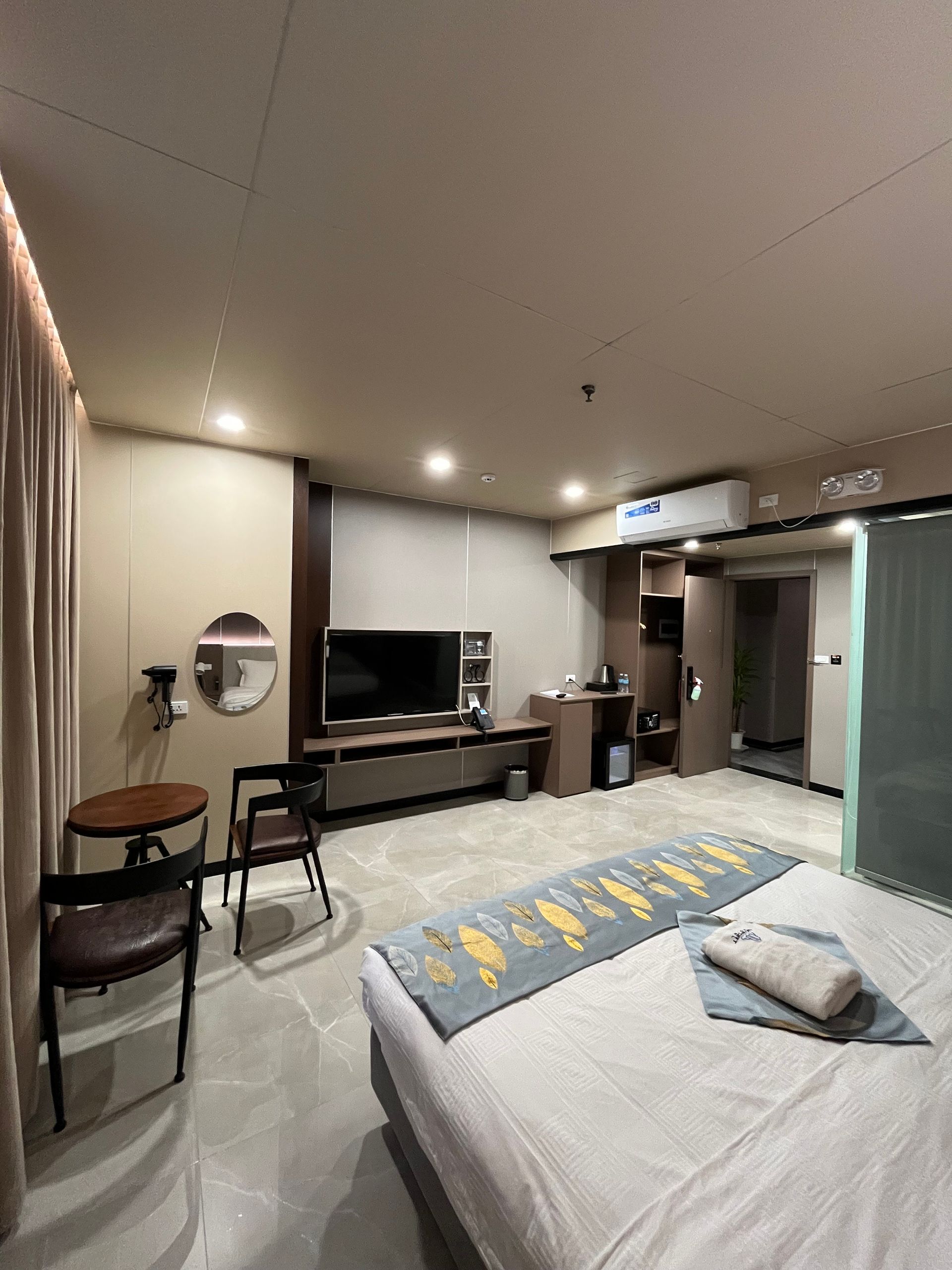 Hotel room with bed, TV, seating area, and sliding glass door.