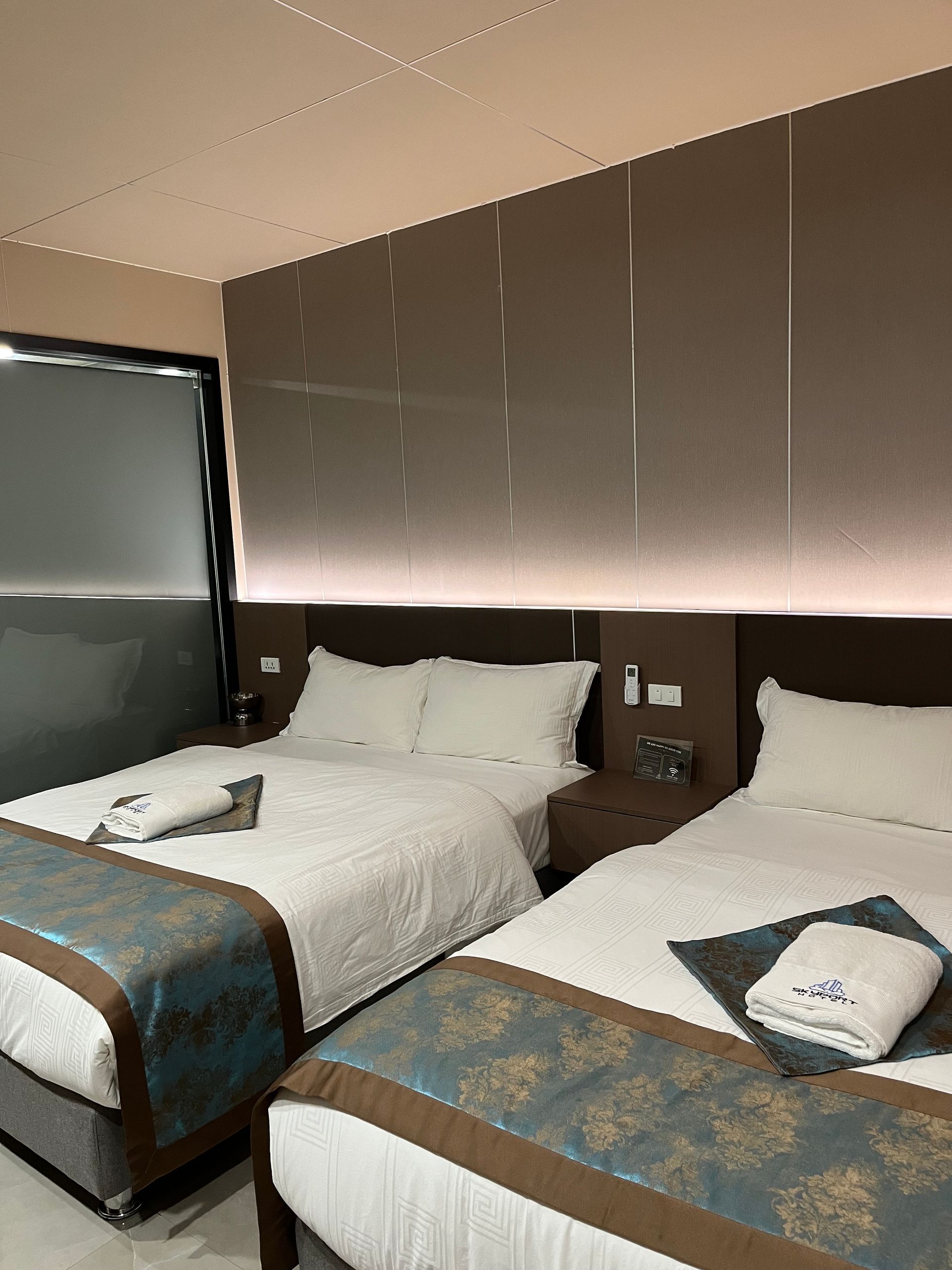 Two beds with white linens, turquoise and brown bed runners in a hotel room.
