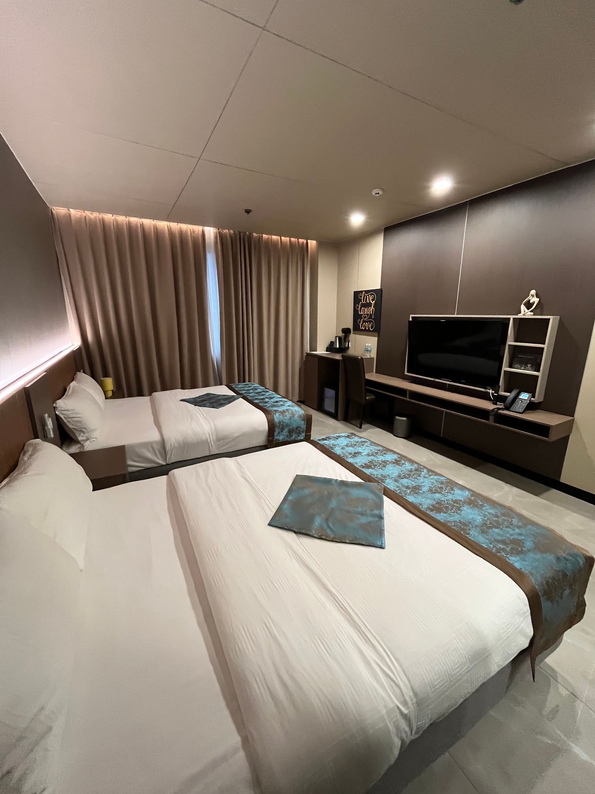 Hotel room with two beds, TV, and neutral-toned decor.