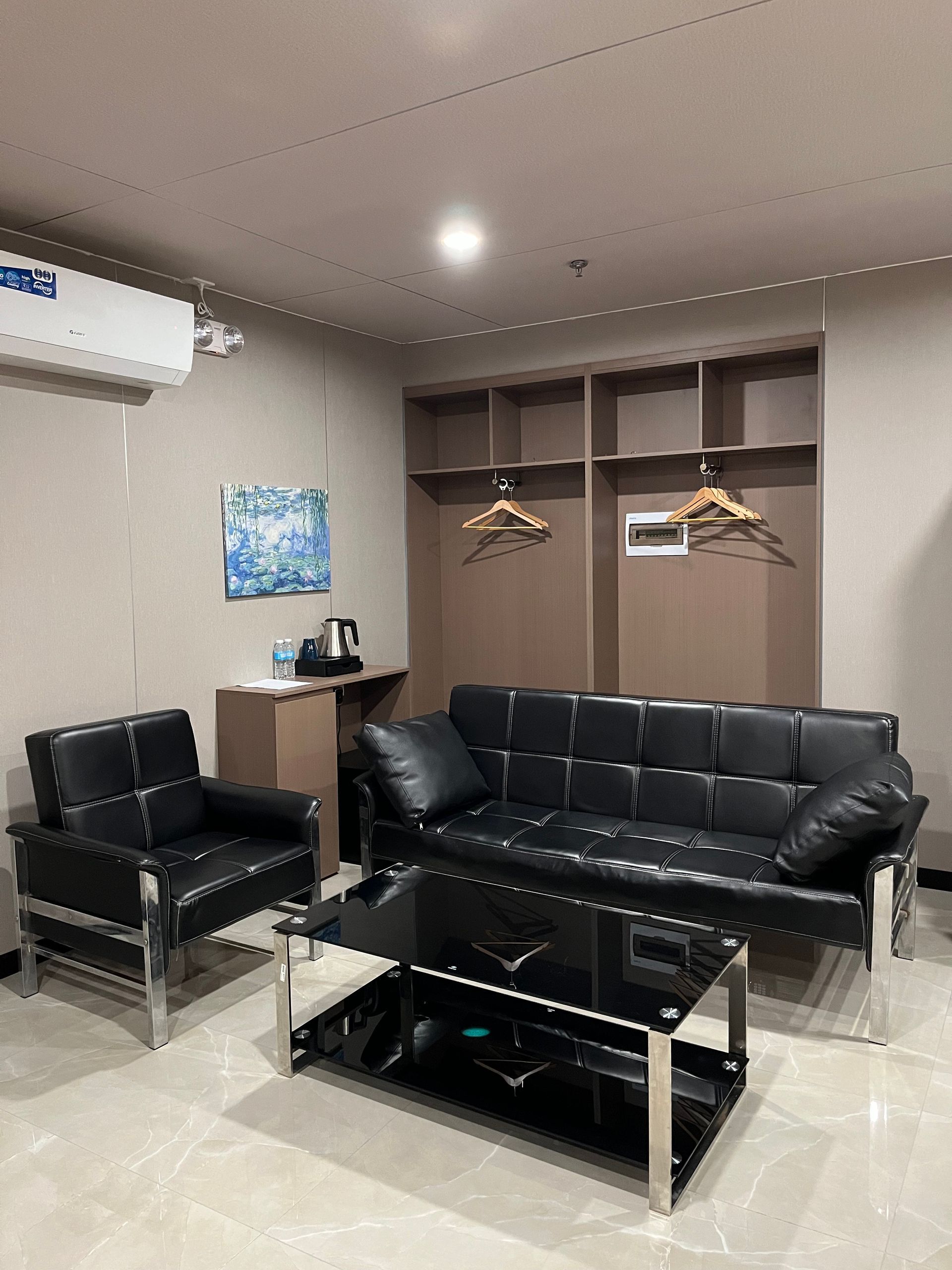 A modern hotel living area with black leather furniture, coffee table, and built-in closet.