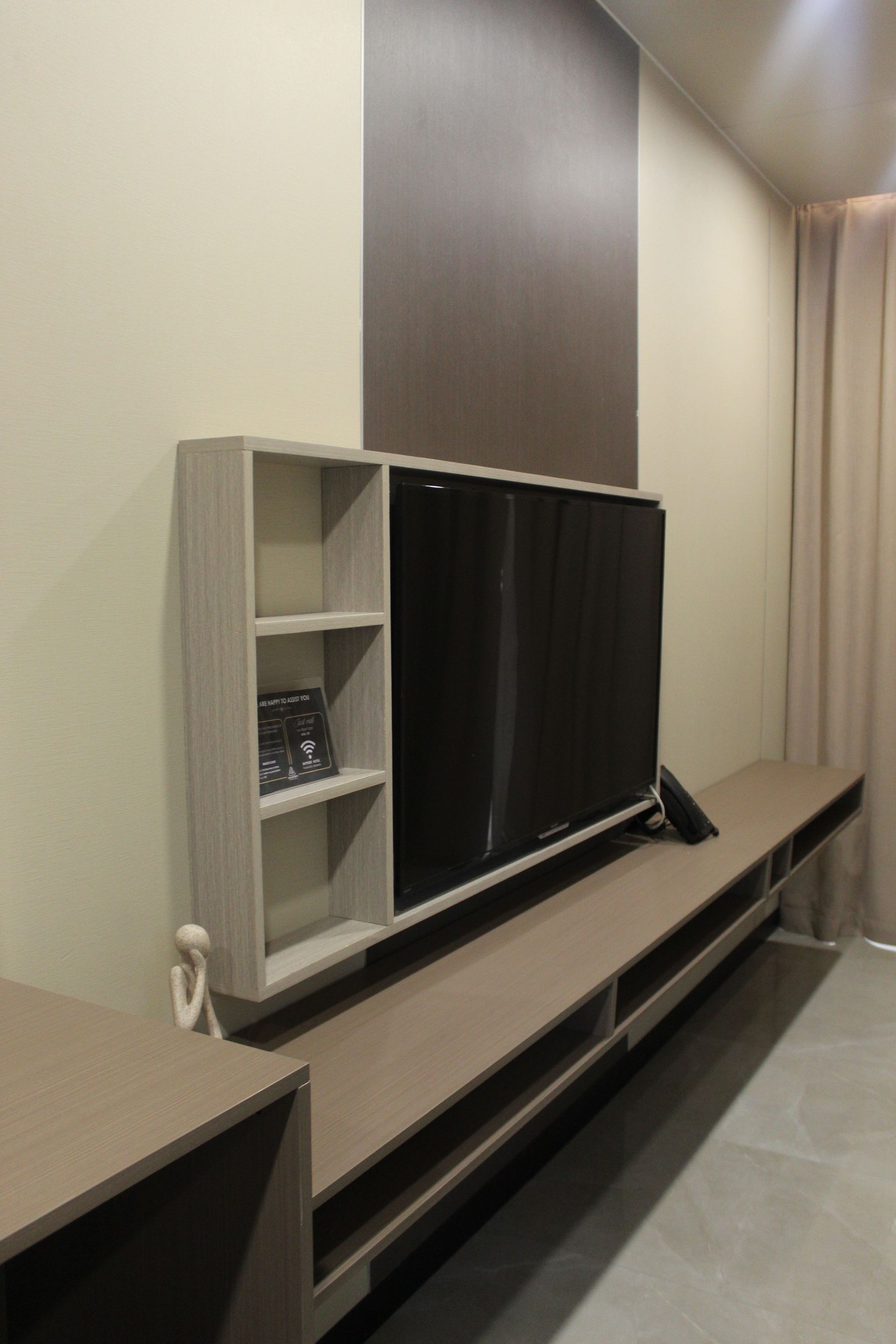 Built-in TV unit on a wall; TV in the center, shelves to the left, and a long shelf underneath.