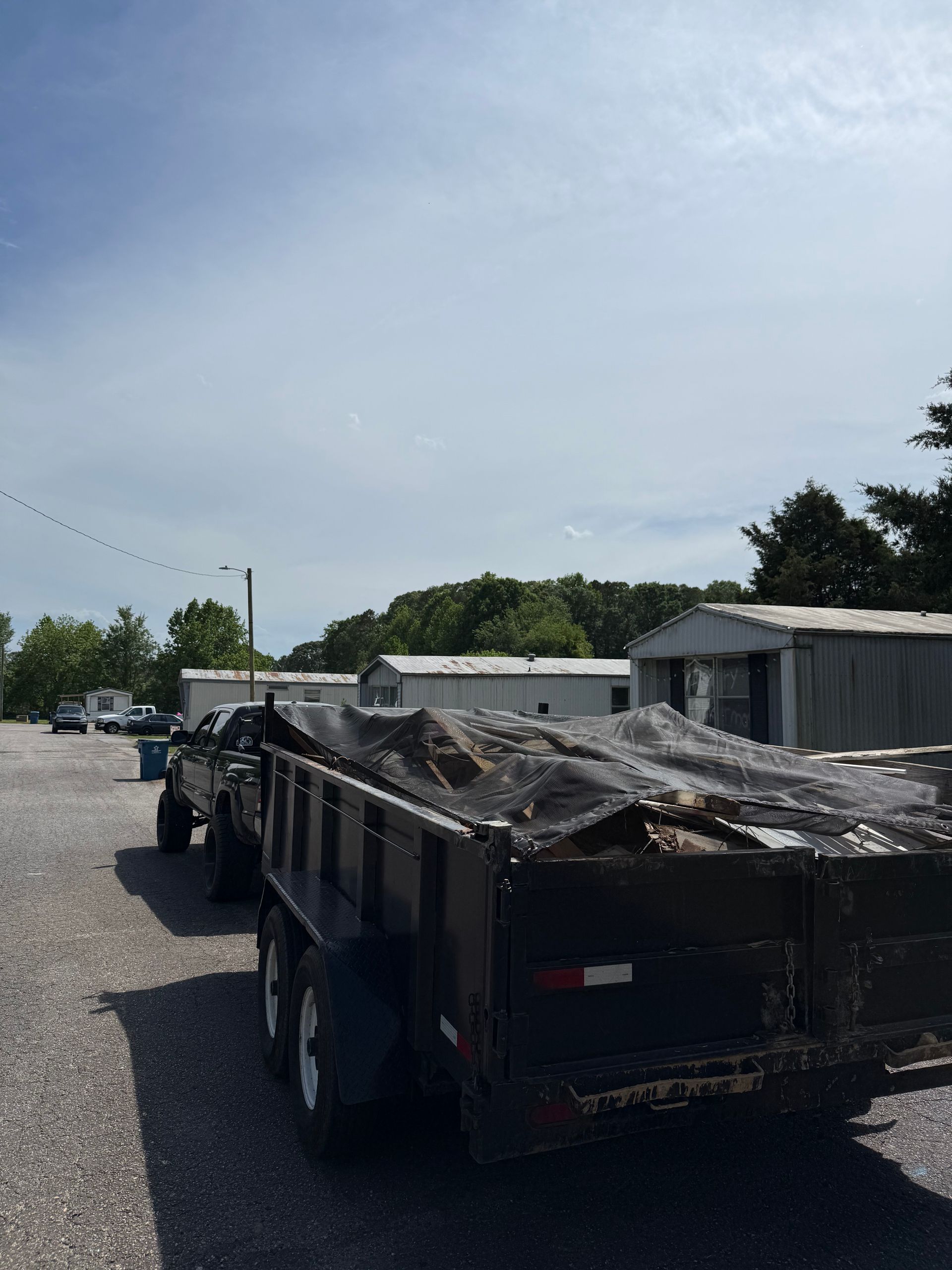 A dump truck is pulling a trailer with a tarp on it
