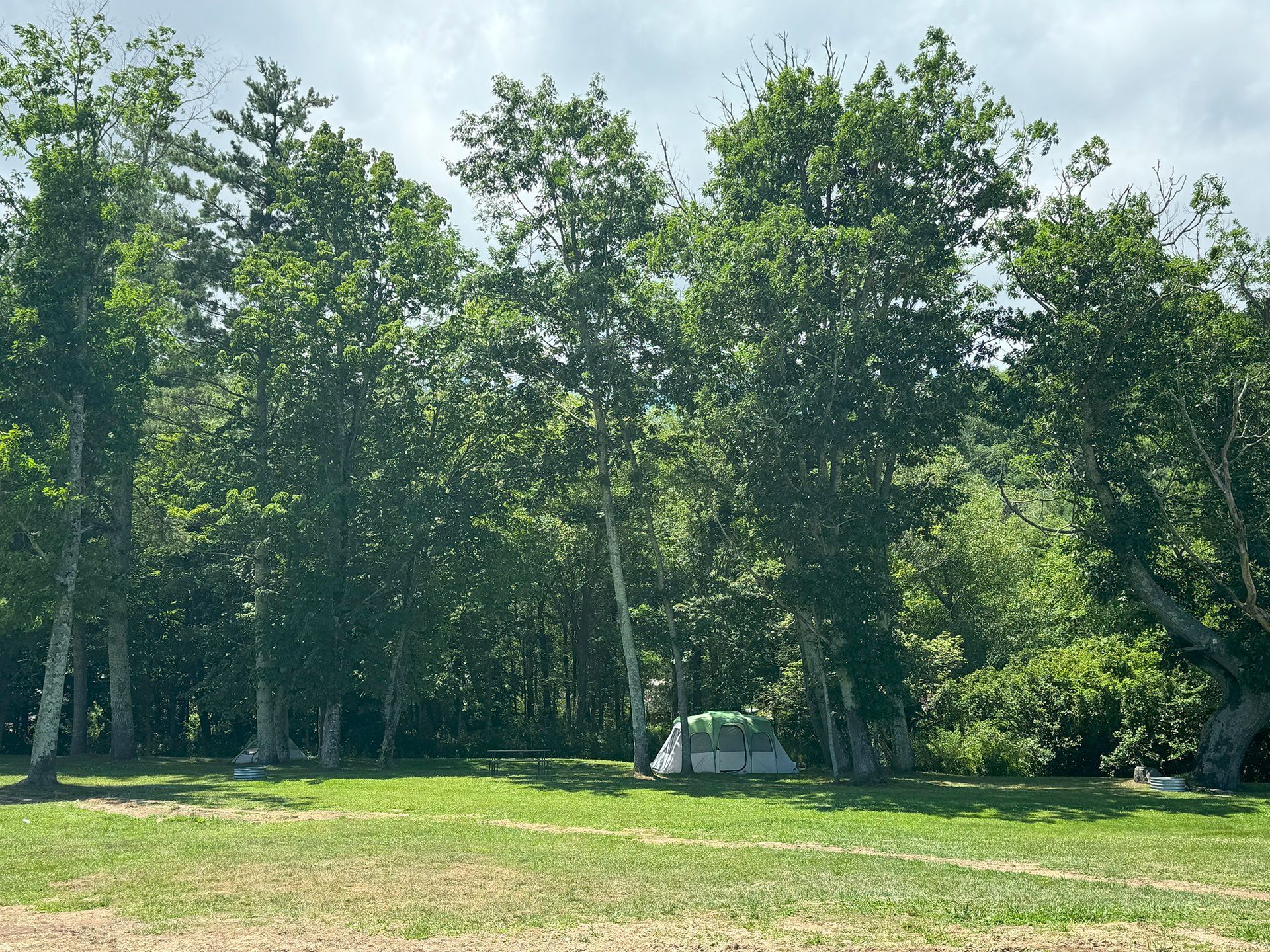 a rv is parked in a grassy field next to a path .