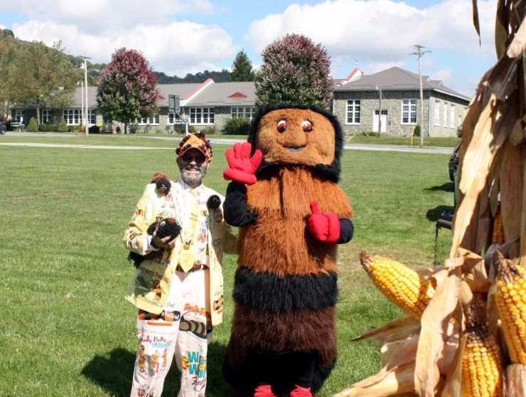 A man in a worm suit stands next to a mascot