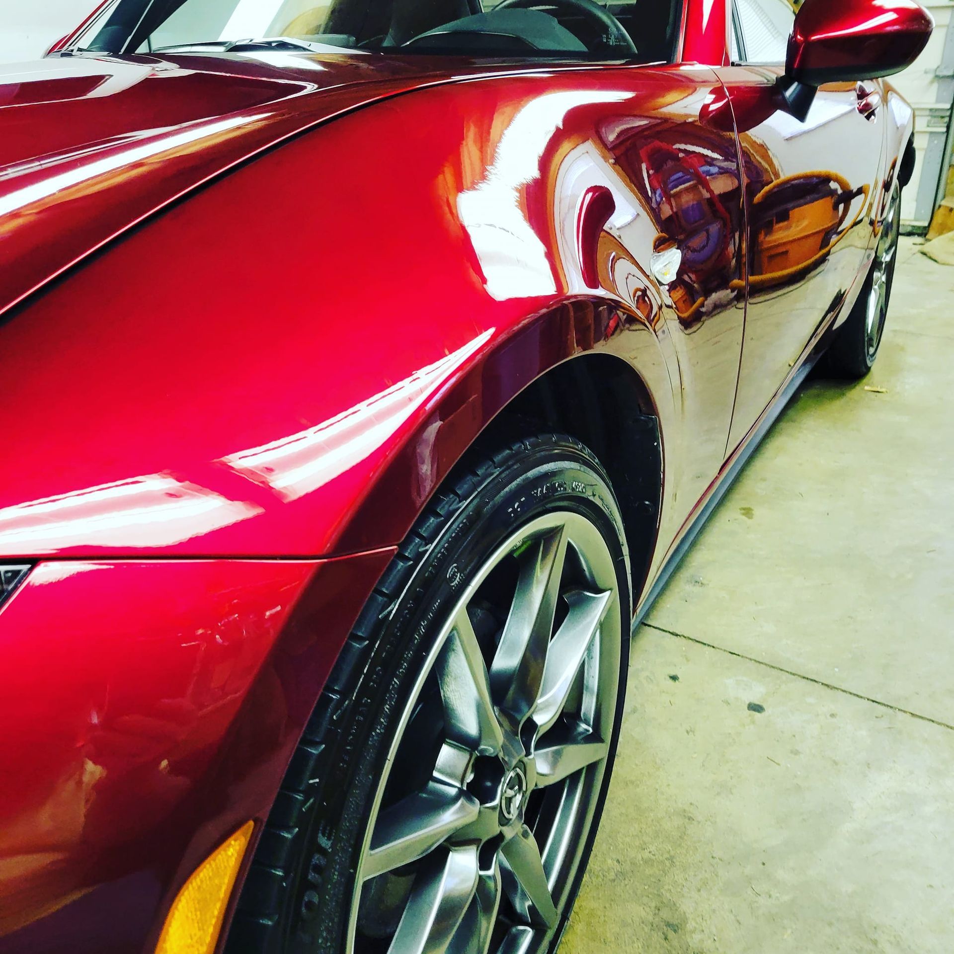 A red sports car is parked in a garage