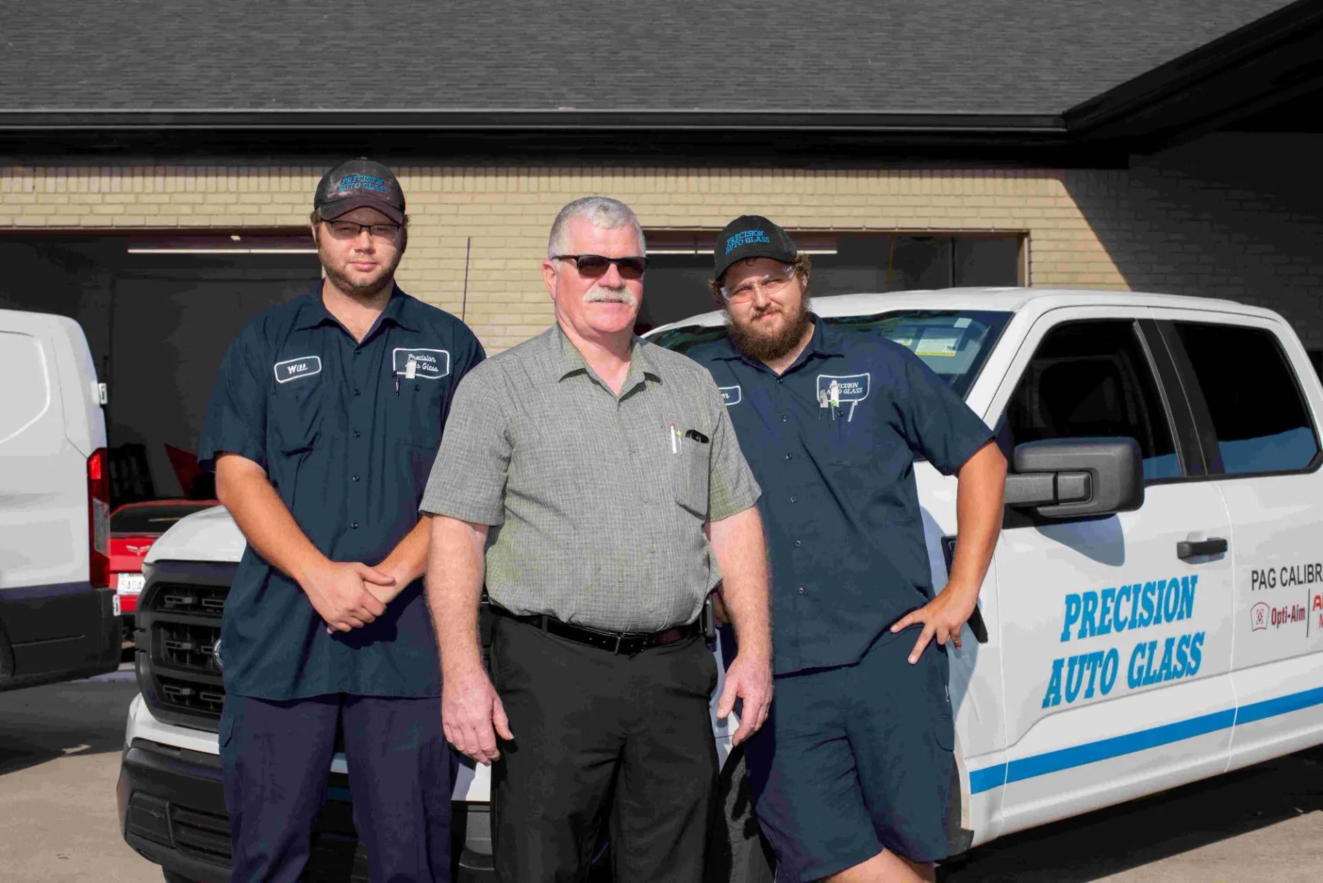 Three men in work uniforms pose next to a white truck with