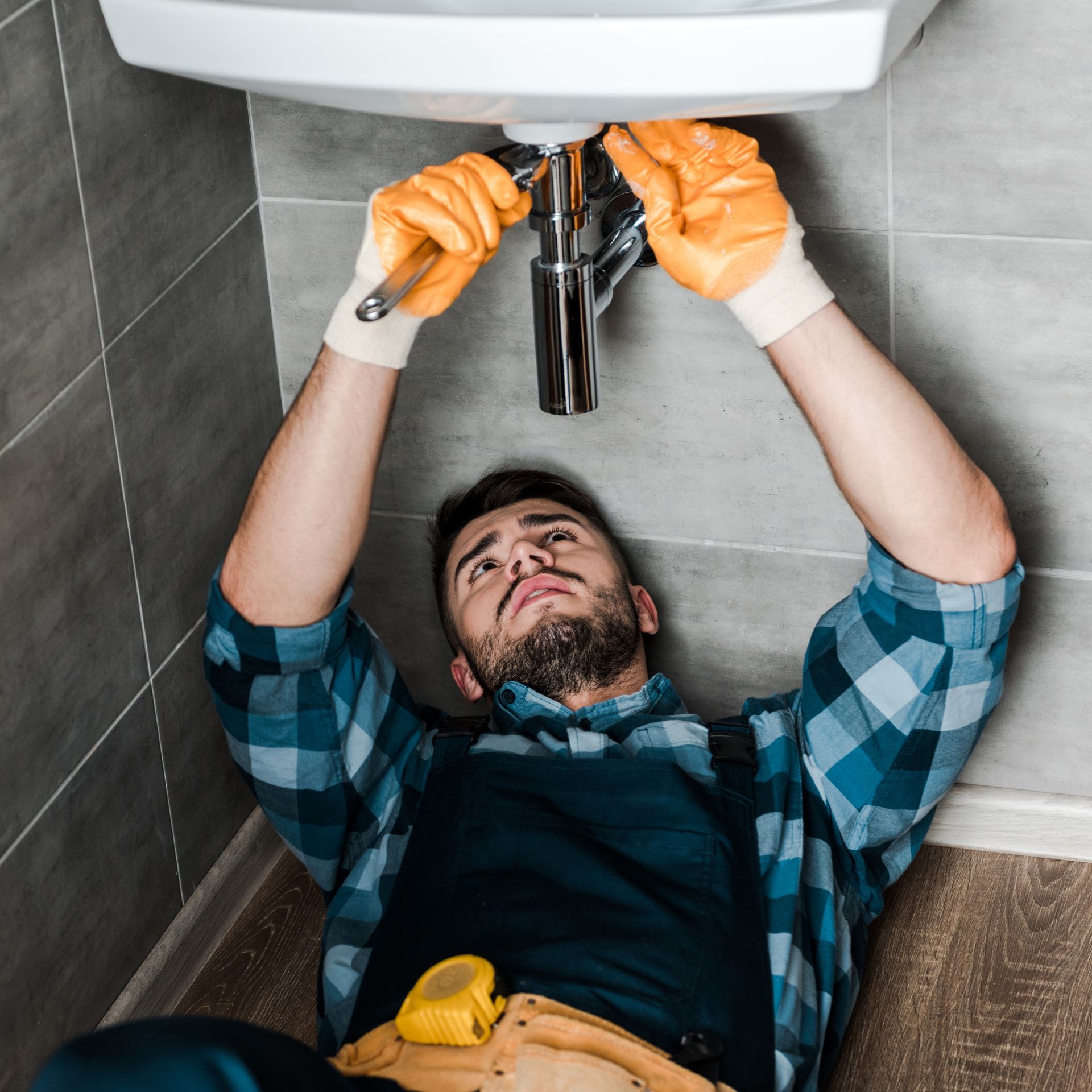 A man is laying on the floor fixing a sink.