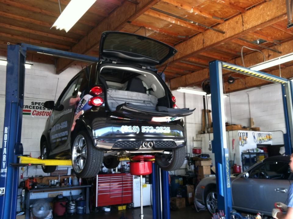 Black Smart car on a lift in a garage with the trunk open. Black Smart car on a lift in a garage with the trunk open.