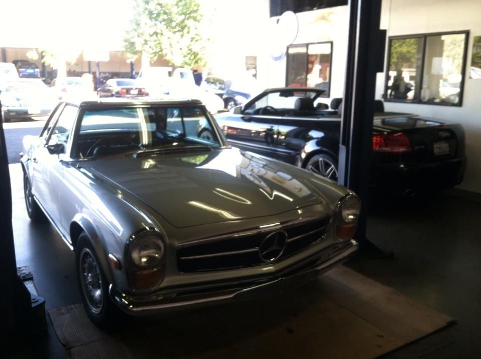 Silver Mercedes convertible in a garage, other cars visible, sunny day. Silver Mercedes convertible in a garage, other cars visible, sunny day.