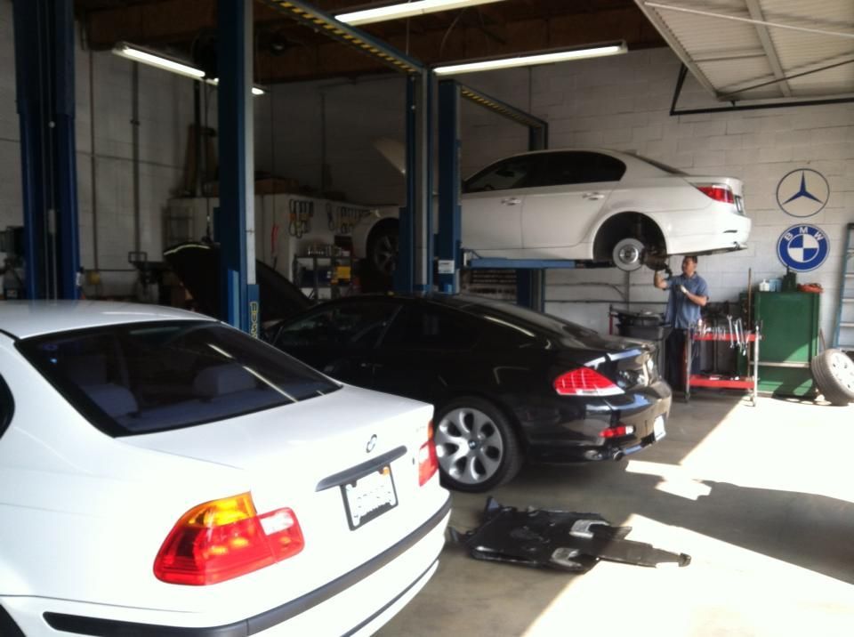 Interior of a car repair shop with several BMWs; a mechanic works on a car lifted on a hoist. Interior of a car repair shop with several BMWs; a mechanic works on a car lifted on a hoist.