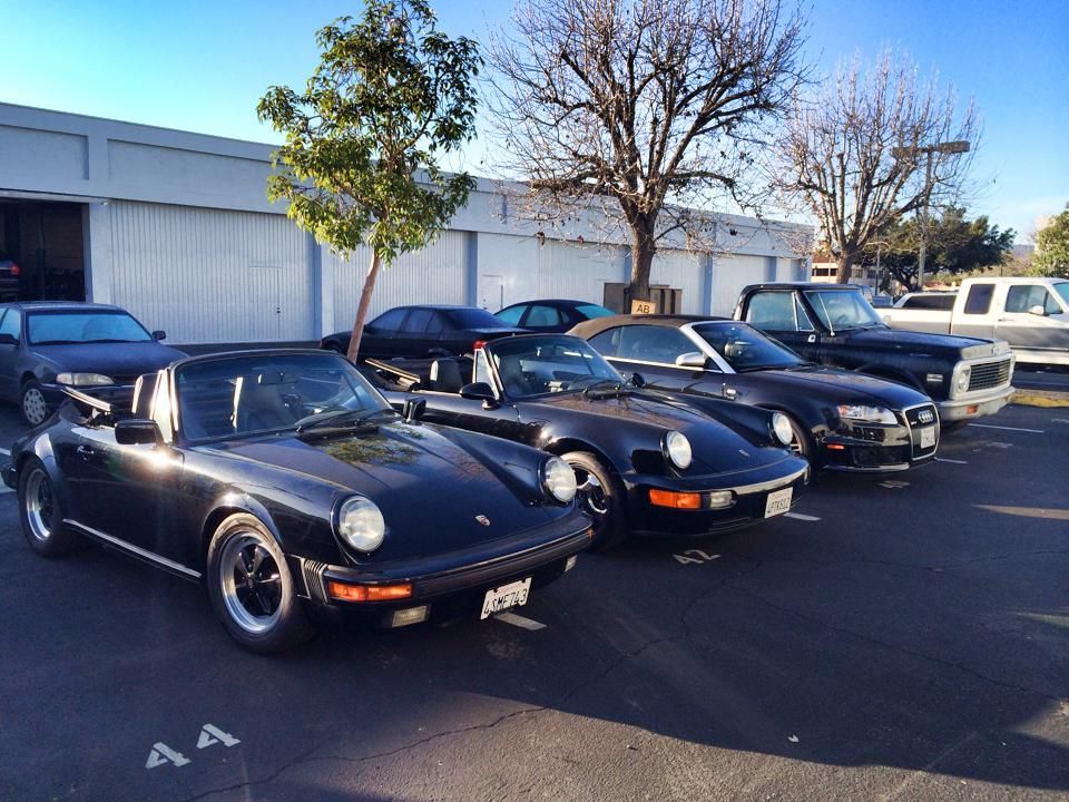 Black classic cars parked outside a building on a sunny day.