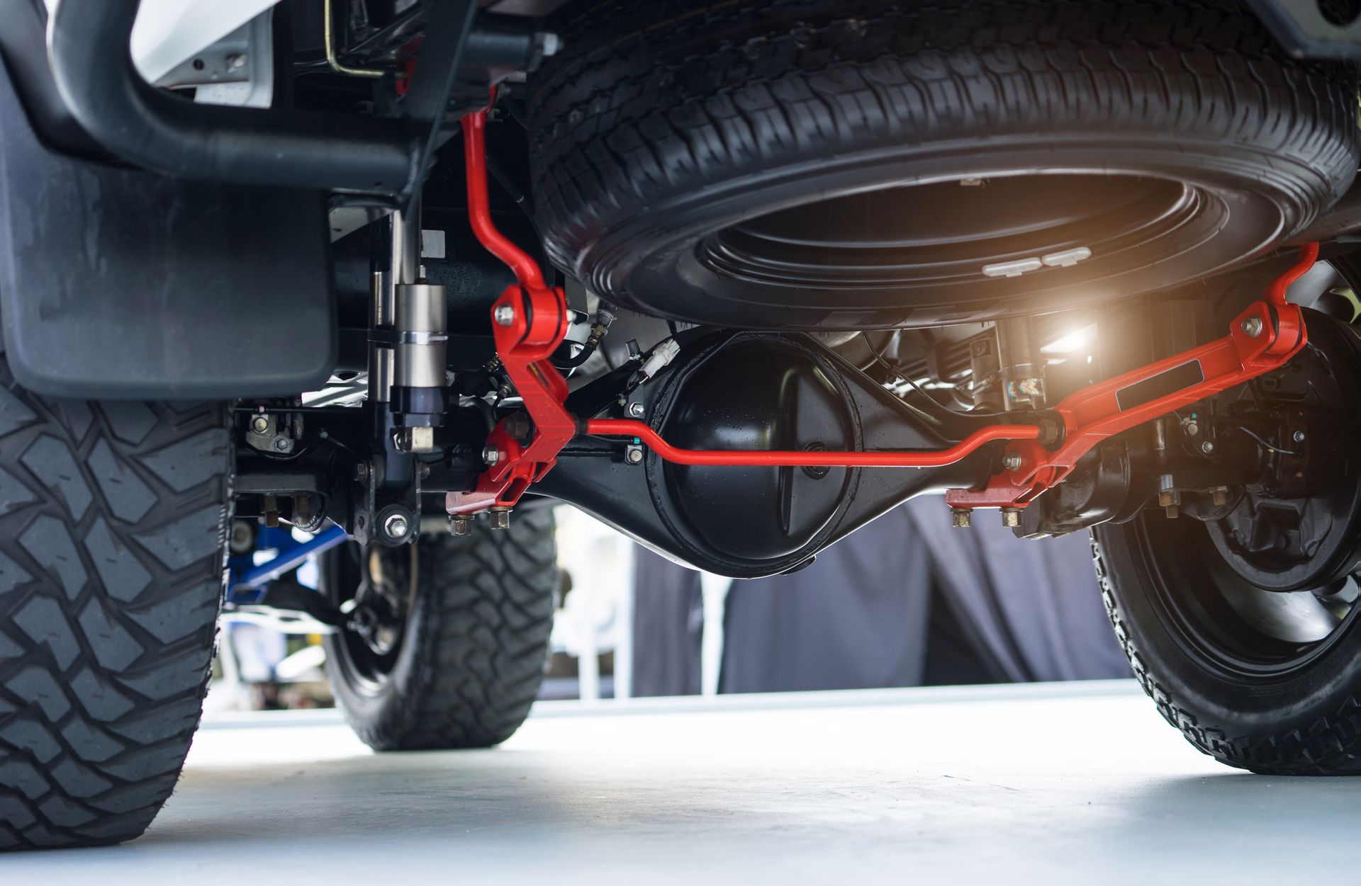 Undercarriage of a pickup truck, showing the rear axle, spare tire, and suspension components painted red.