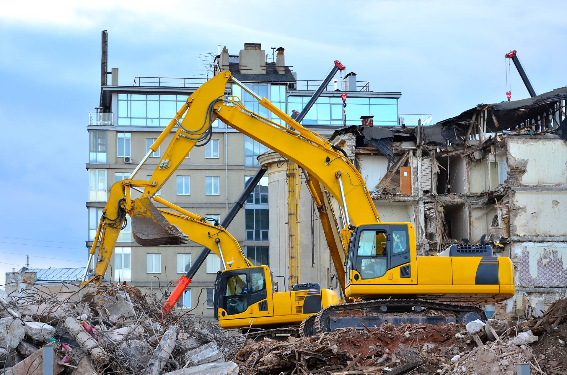 Due escavatori gialli stanno demolendo un edificio.