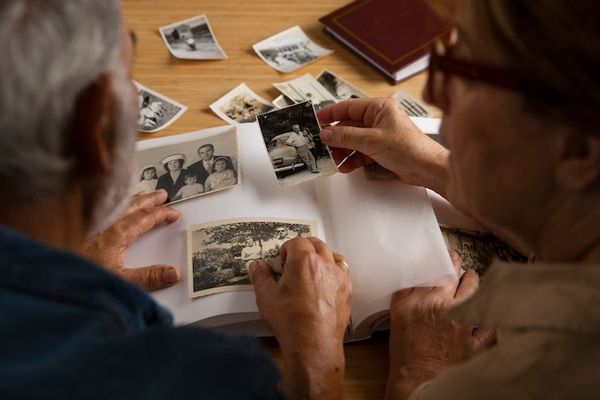 An elderly couple is looking at old photos together.