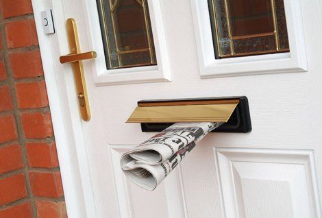 A newspaper sticking out of a letterbox