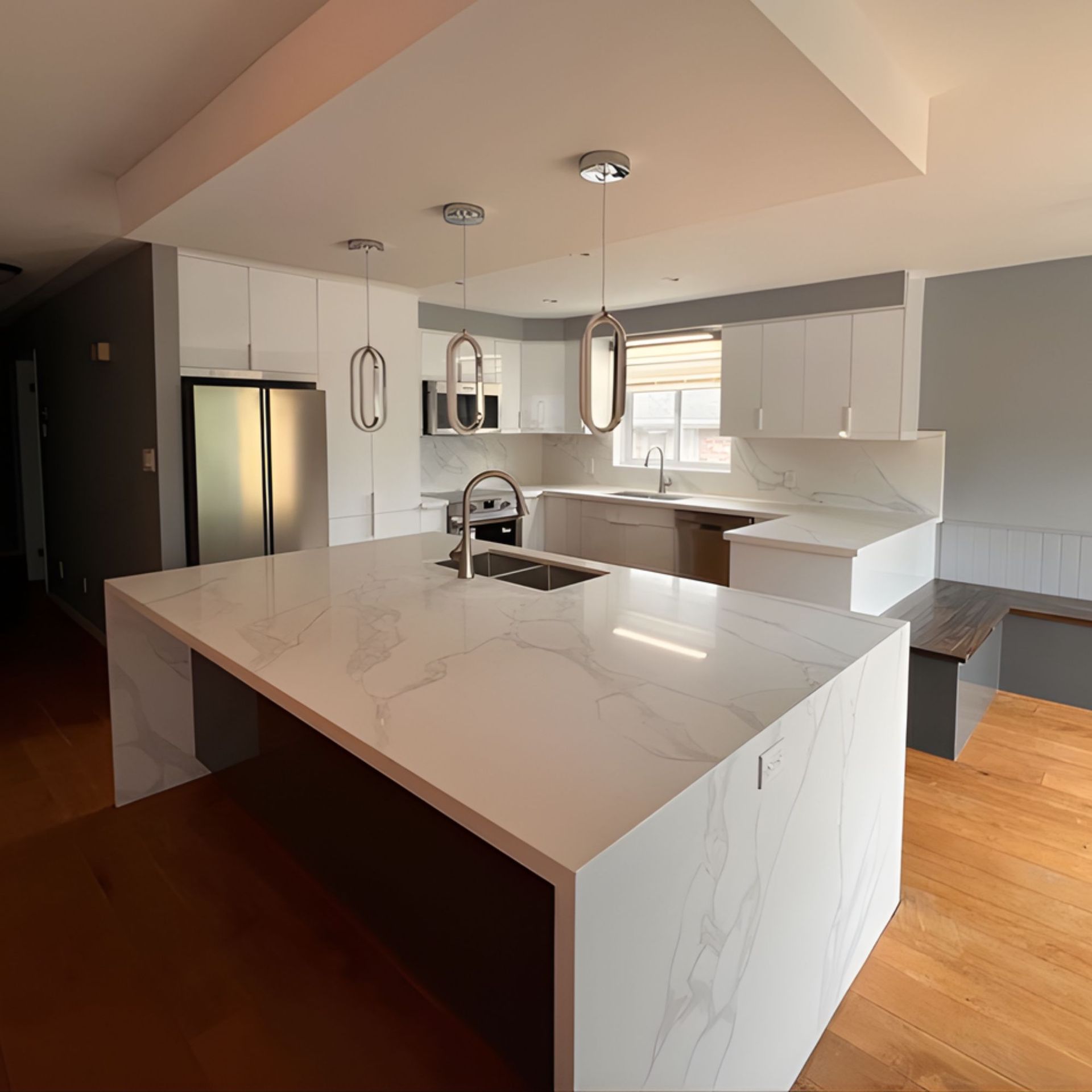 Modern white kitchen with marble countertops, stainless steel appliances, and wood floors.