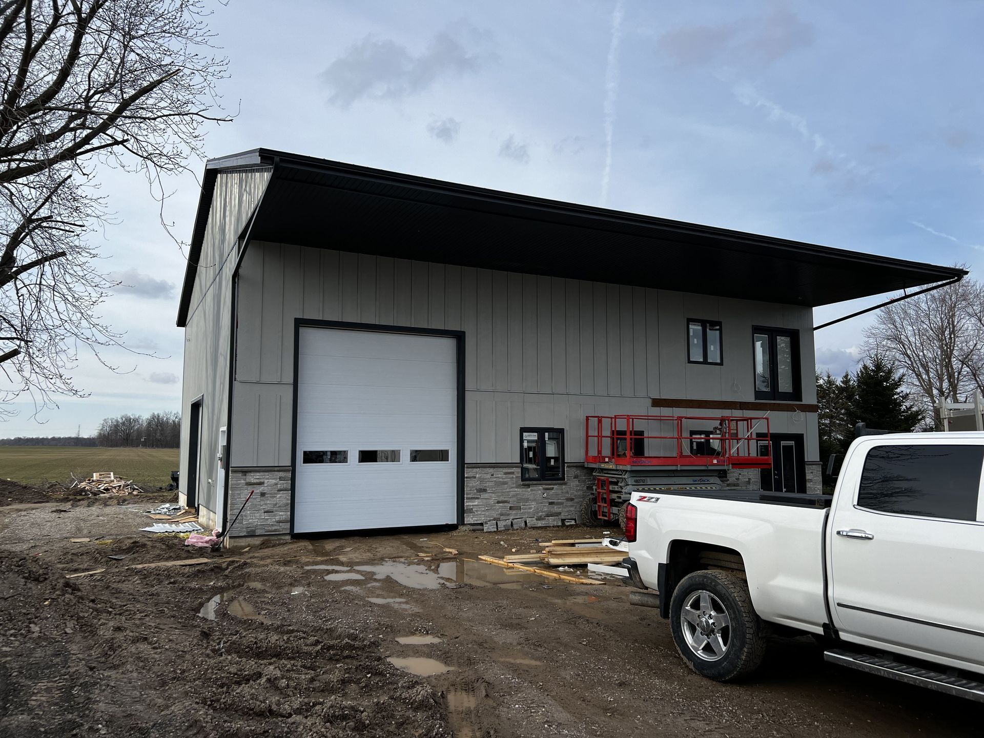 A white truck is parked in front of a building under construction.