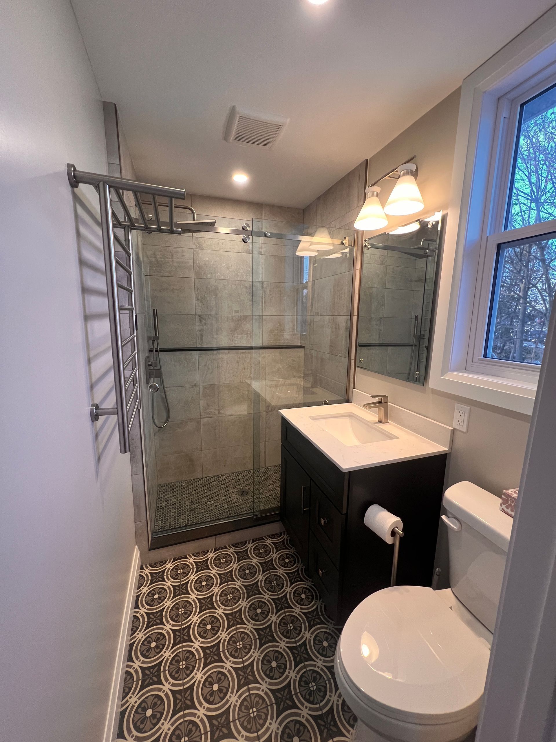 Creative Home Solutions - Bathroom with shower, vanity, toilet, and patterned tile floor.