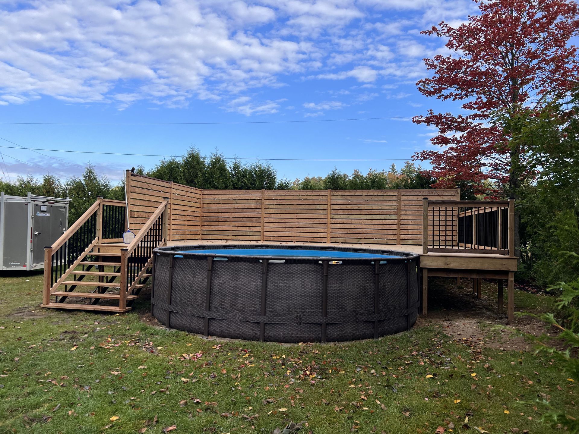 A large swimming pool is sitting on top of a wooden deck.