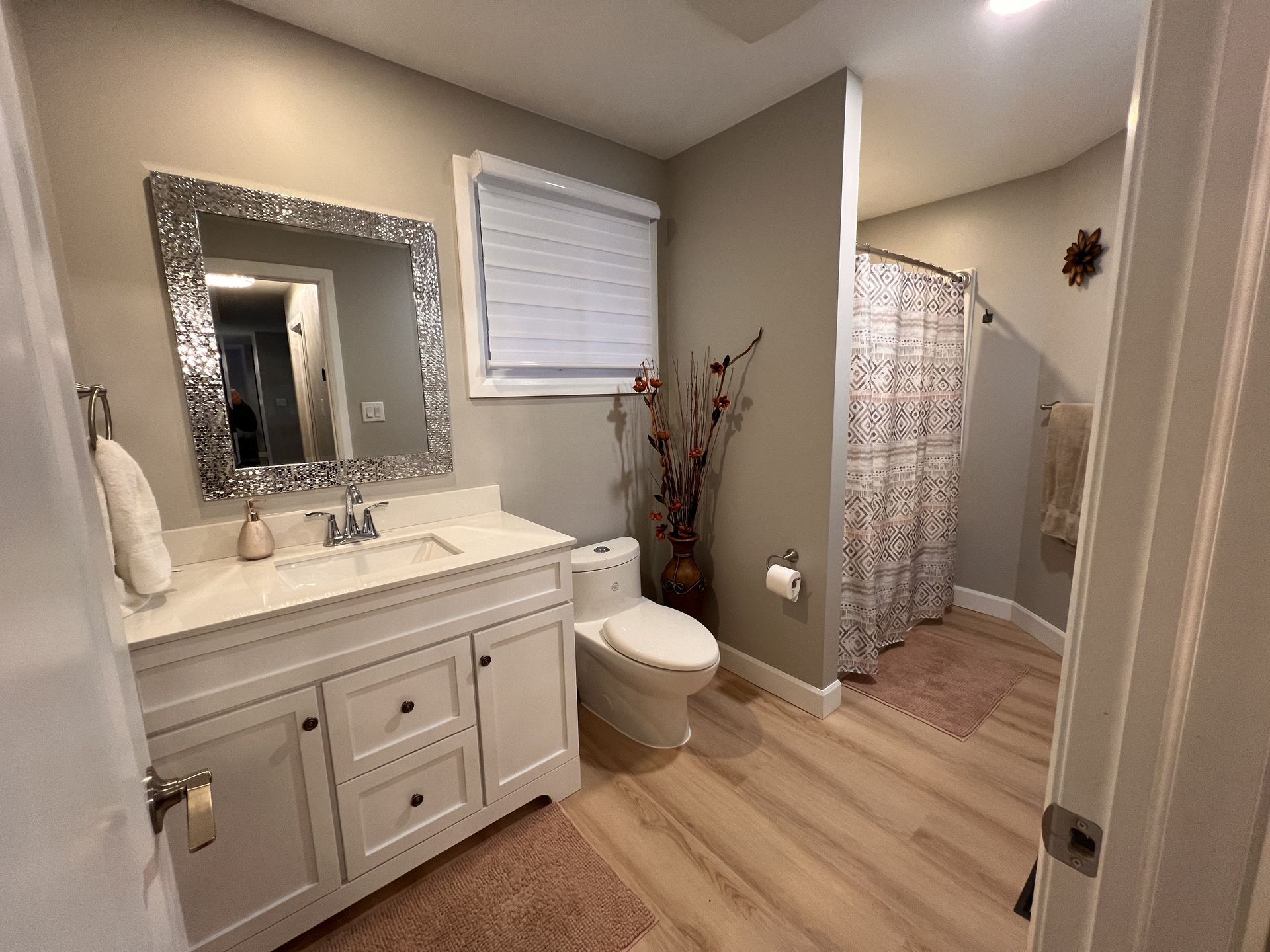 A bathroom with a toilet , sink , mirror and shower curtain.