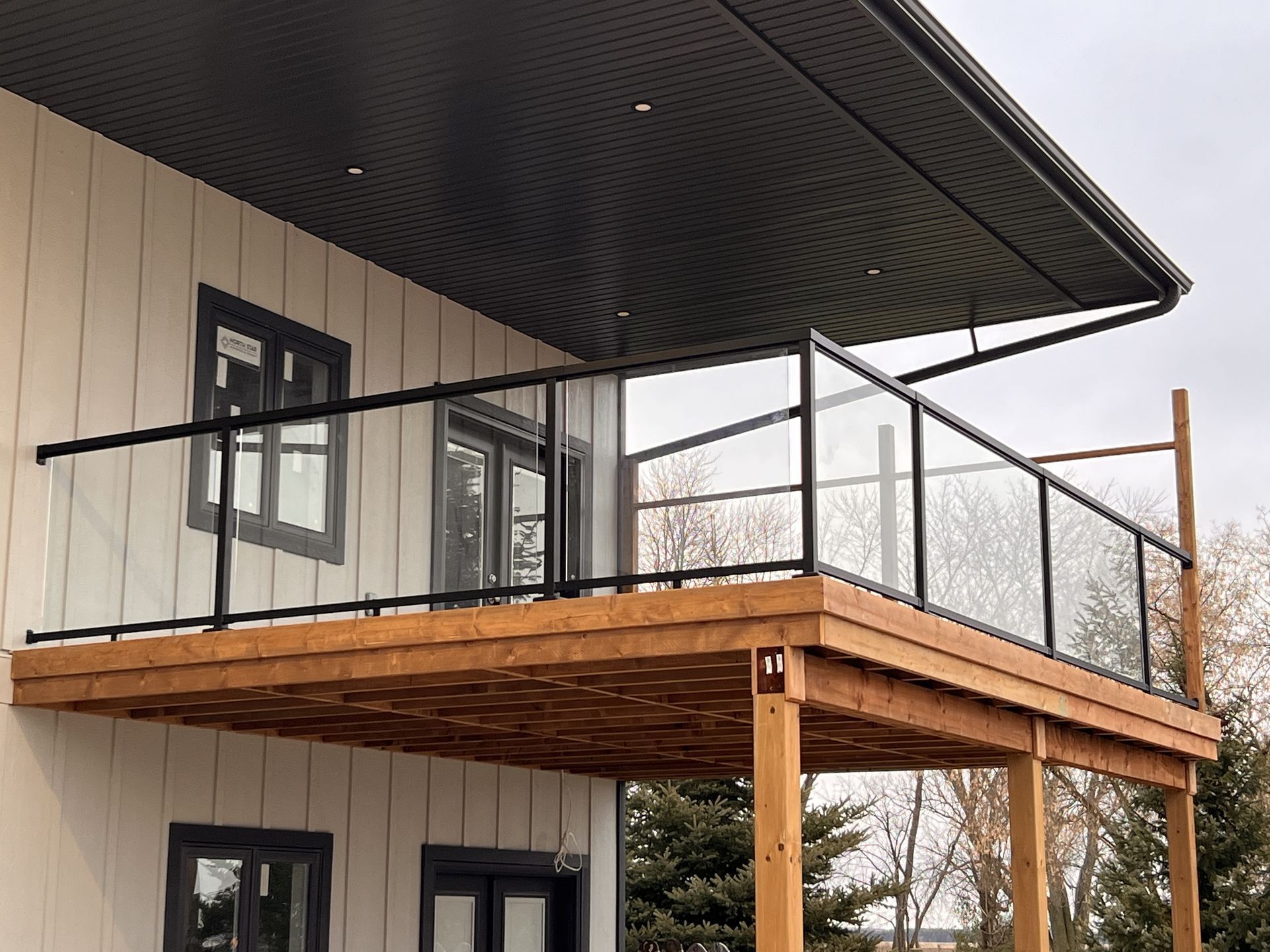 A balcony with a glass railing on the side of a house.