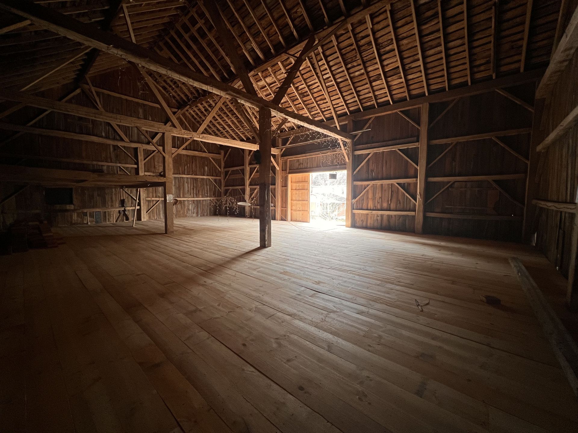 The inside of an old barn with wooden floors and a roof.