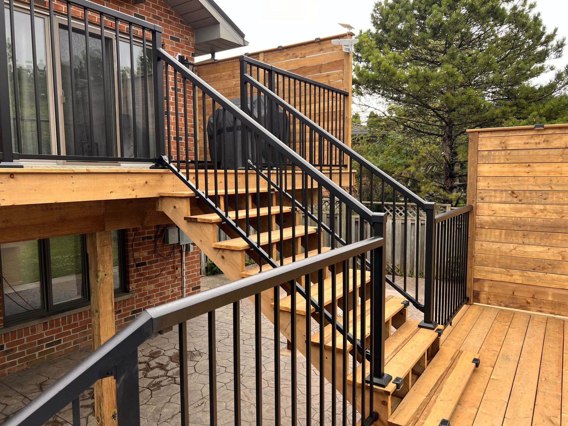 A wooden deck with stairs leading up to it and a metal railing.