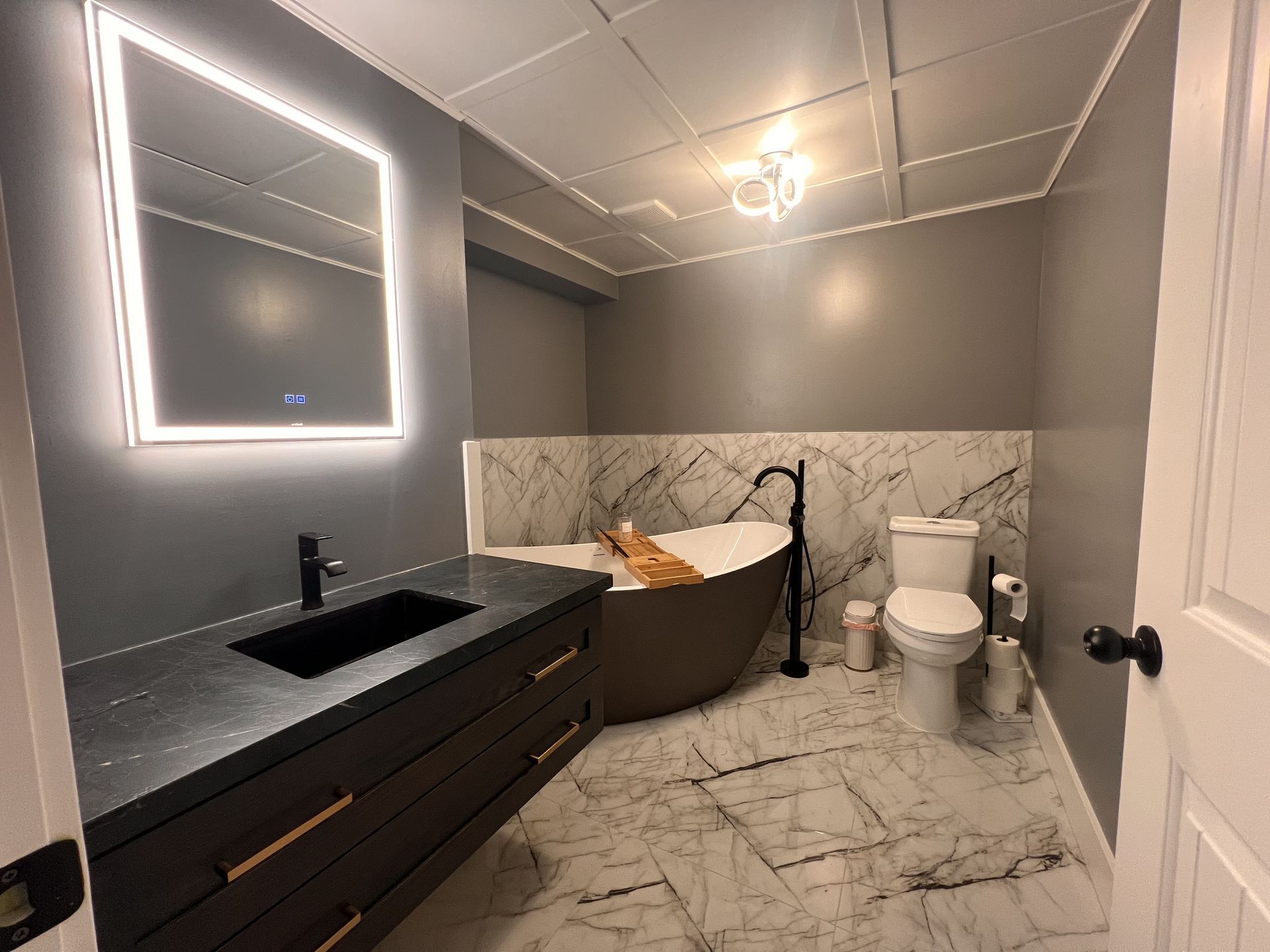 A bathroom with a tub , toilet , sink and mirror.