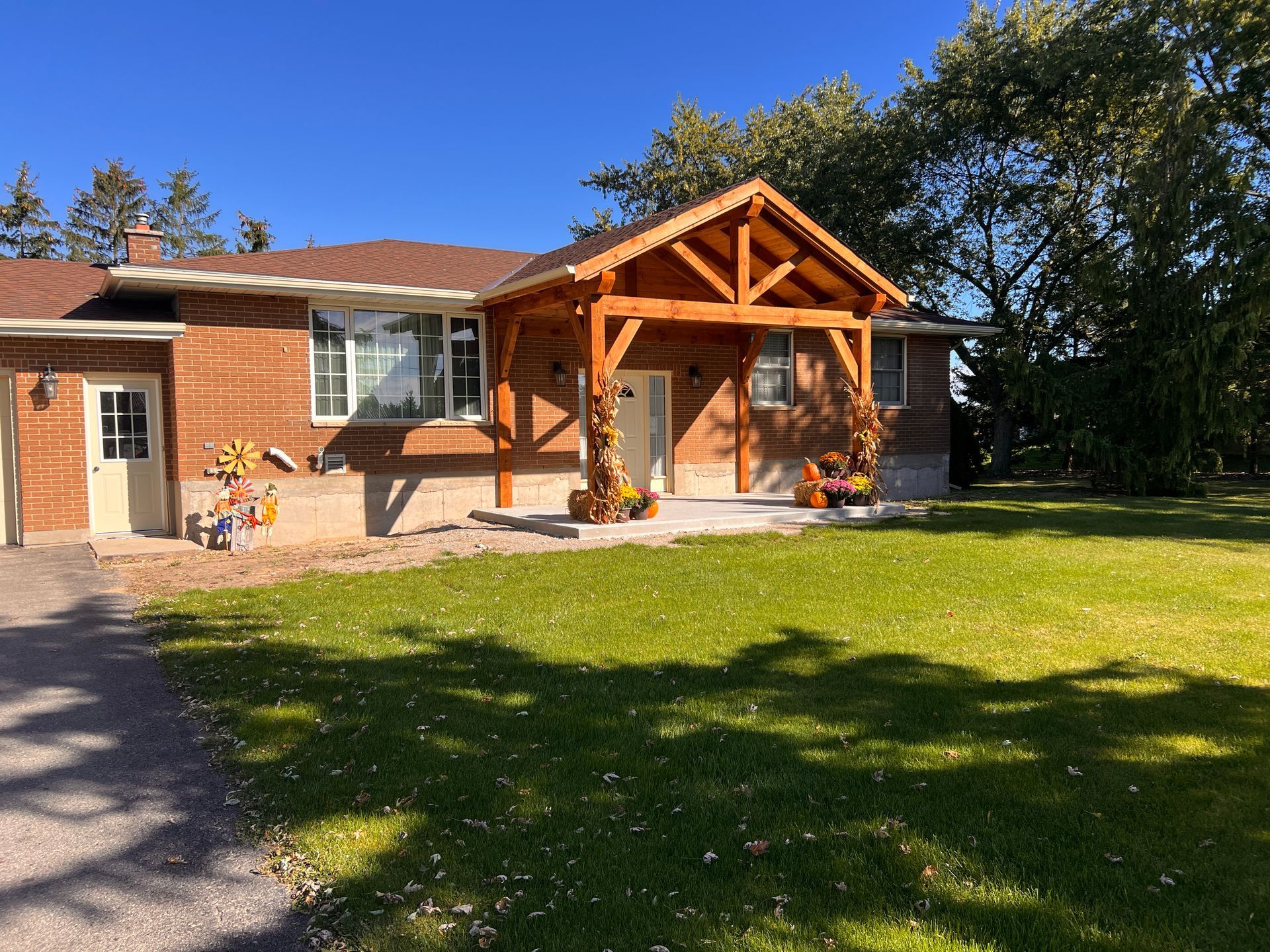 A brick house with a wooden porch and a large lawn