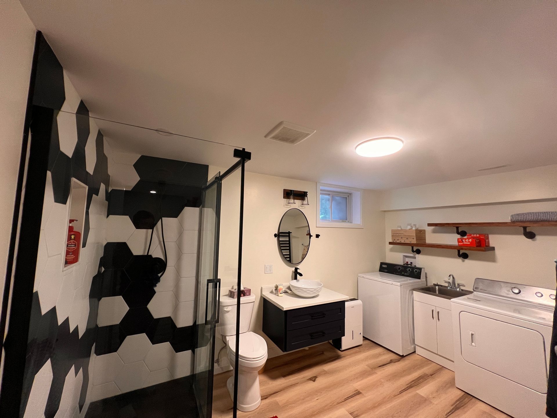A bathroom with a toilet , sink , washer and dryer.