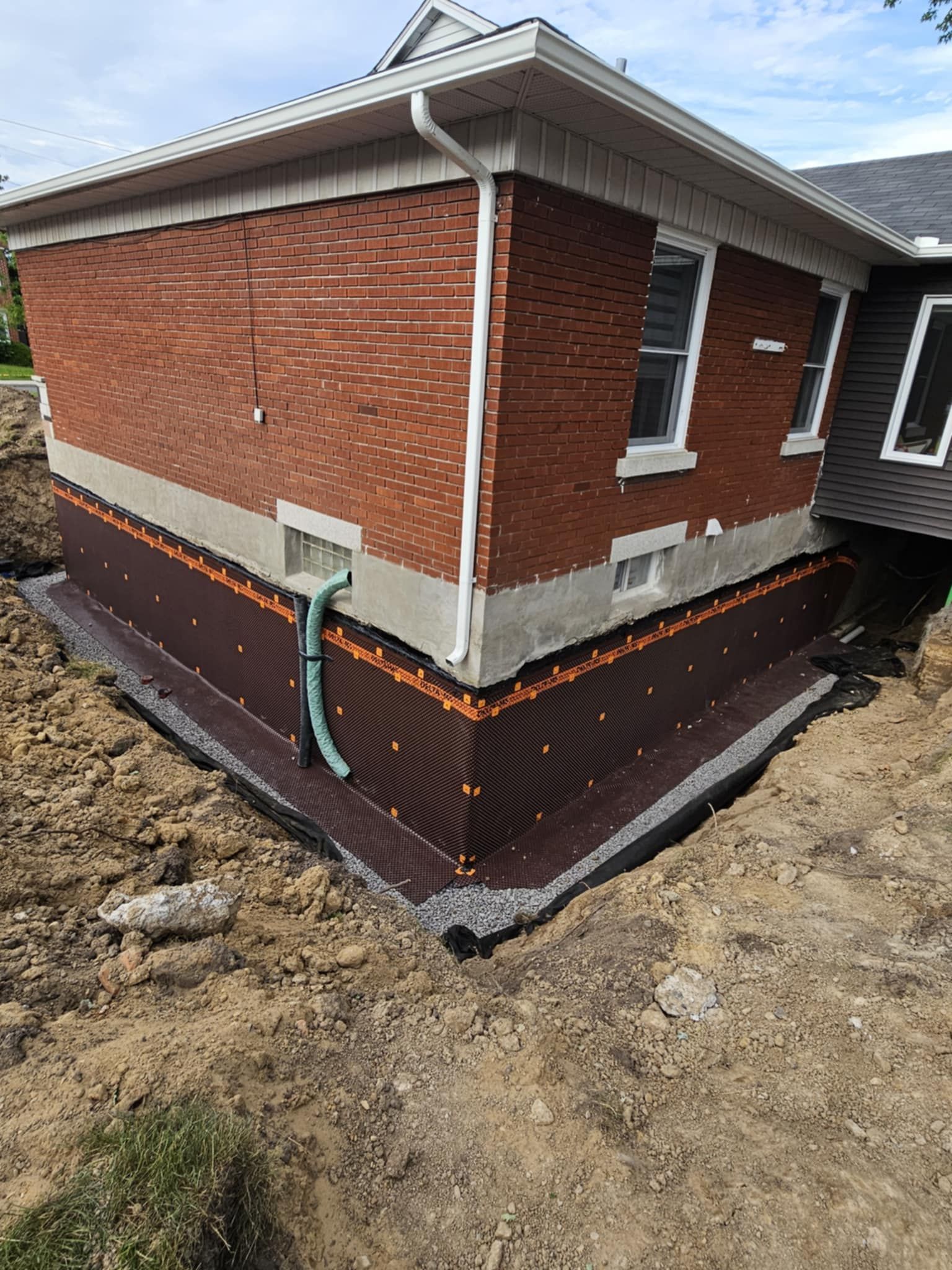 Une maison en briques avec un système de drainage installé sur le côté.