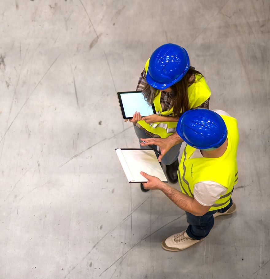 Un homme et une femme portant des casques de sécurité regardent une tablette