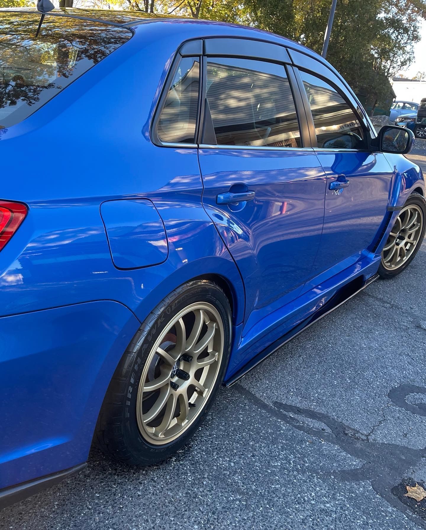 A blue car with gold wheels is parked on the side of the road.