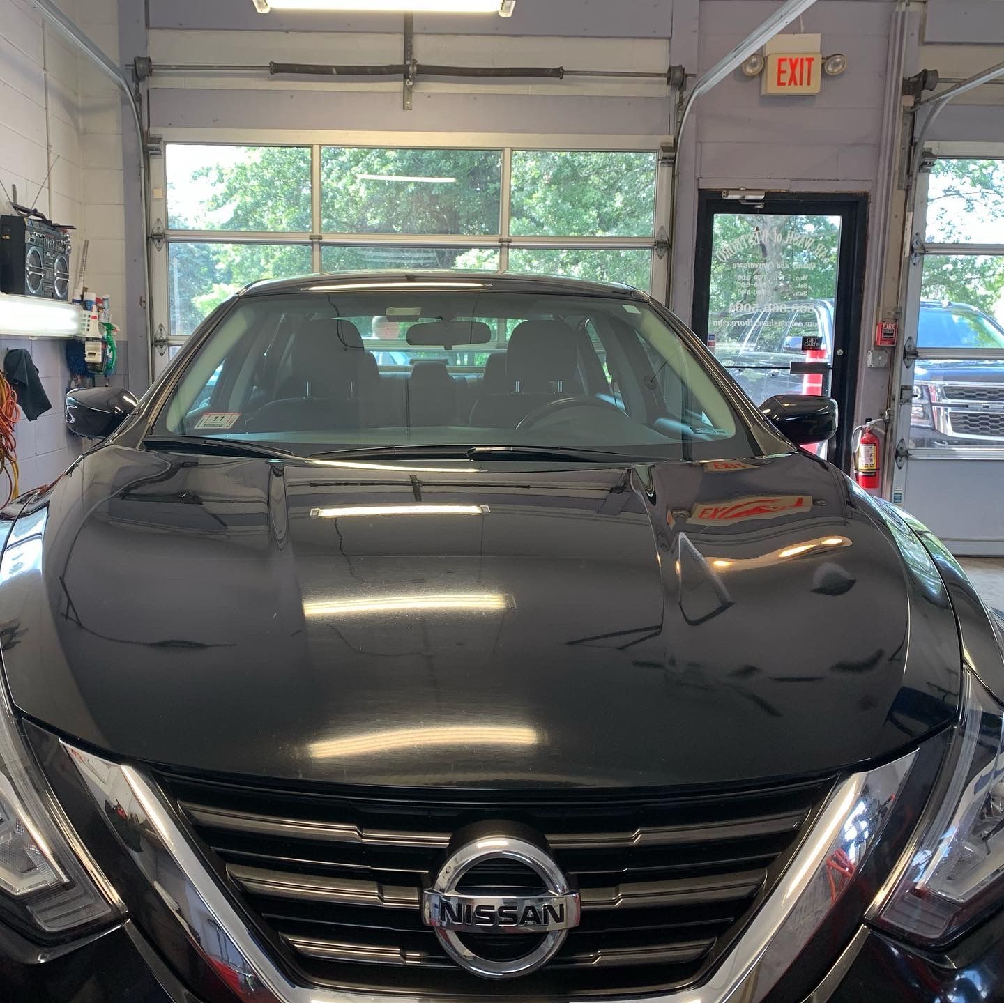A black nissan car is parked in a garage