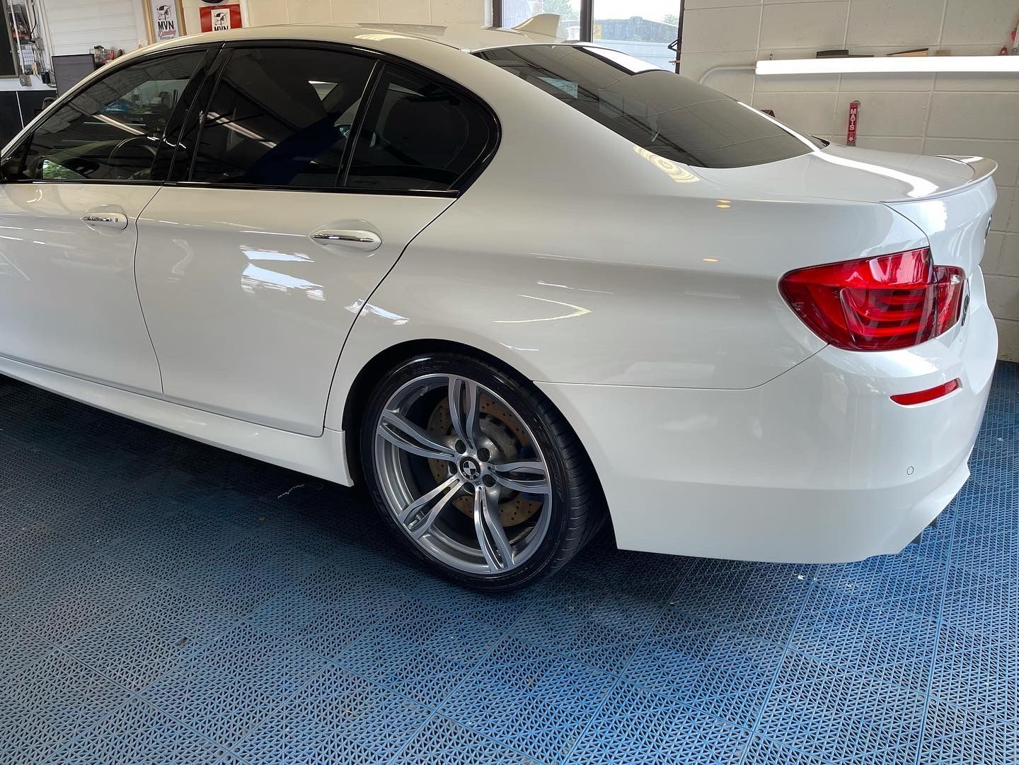 A white bmw 5 series is parked in a garage.